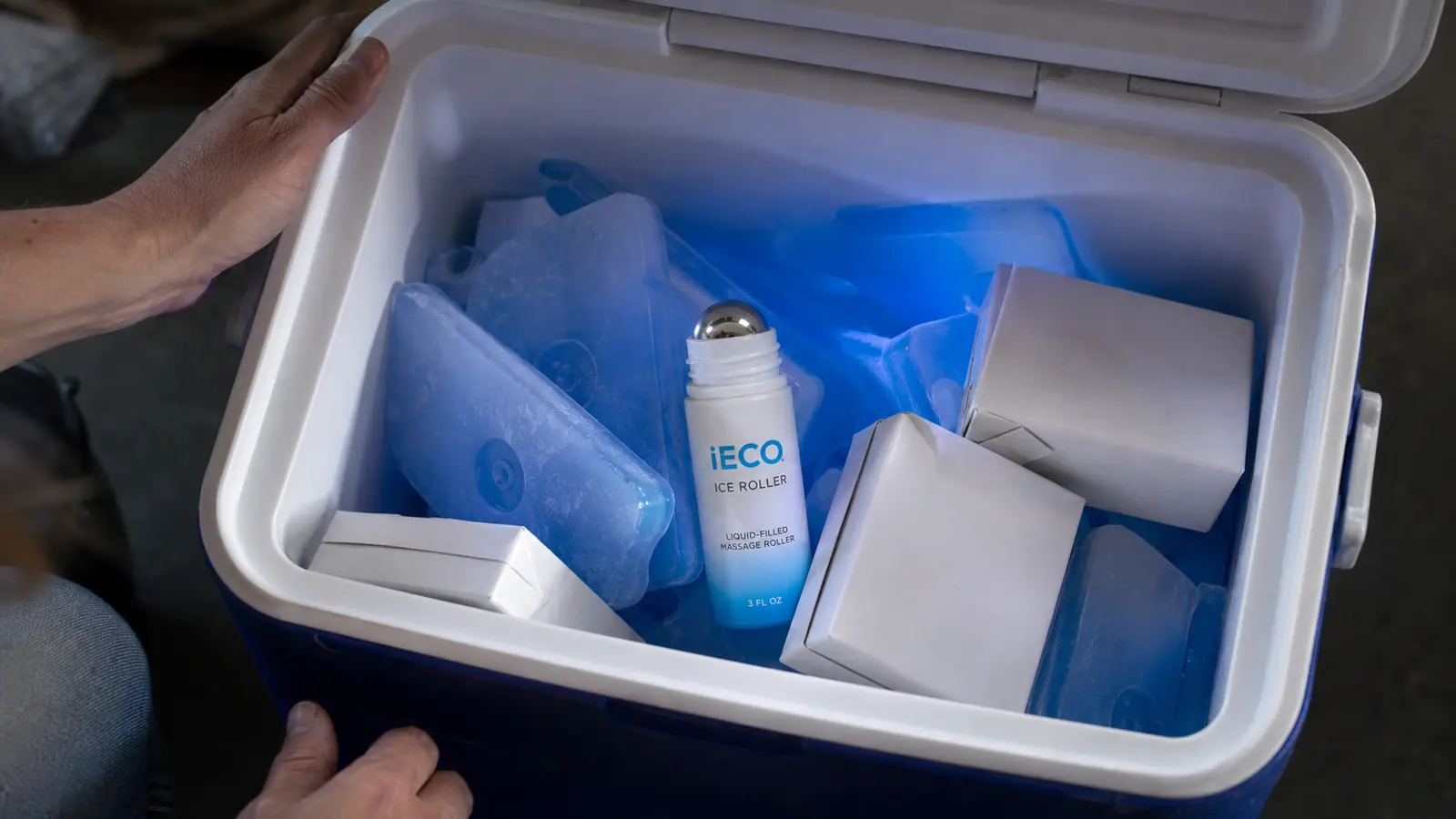 Small ice roller resting inside an open cooler next to gel ice packs and juice boxes